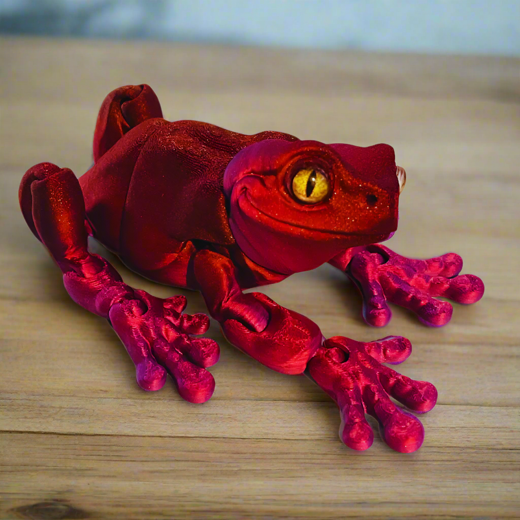 Stretched-out view of a 3D printed tree frog in red and purple, highlighting the full length of its body and the detailed texture of its skin.