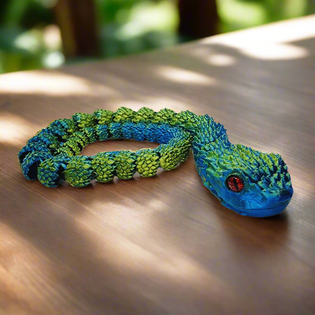 3D printed copperhead snake toy fully stretched out, showing its flexible, articulating joints and blue and yellow color scheme, 26 inches long.