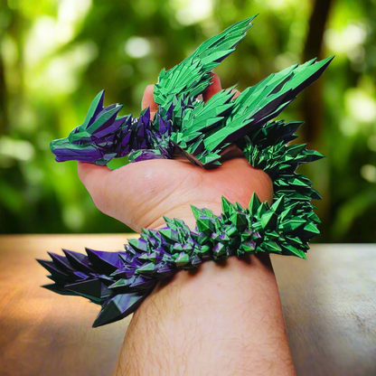 3D printed crystal-wing dragon toy in purple and green silk, wrapped around a person’s arm, showing its flexible and articulated design, 20 inches long.