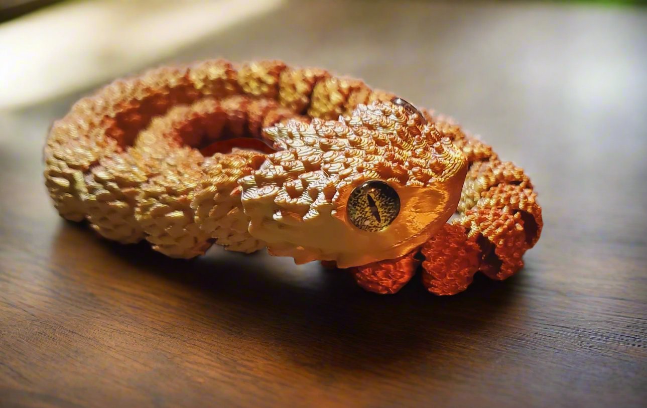 A golden snake figure coiled up with a lifelike amber eye, displaying intricate scale texture and shading.