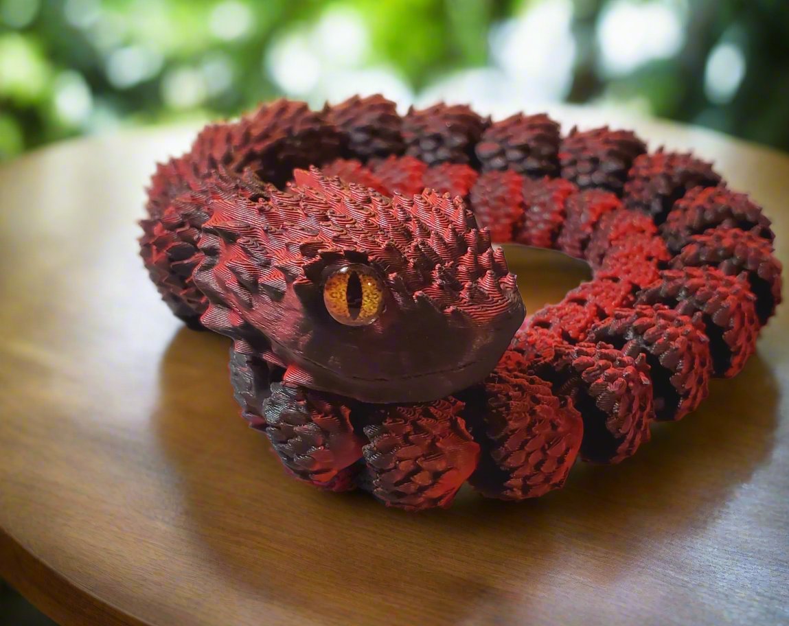 A red and black snake figure coiled up with its bright amber eye and spiky scales prominently displayed.