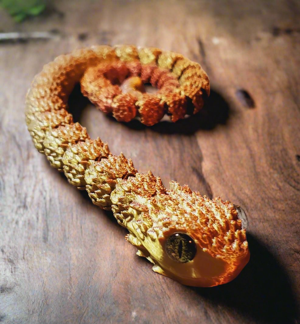 Full view of a golden and orange articulated snake figure, featuring its realistic amber eyes and detailed scales.