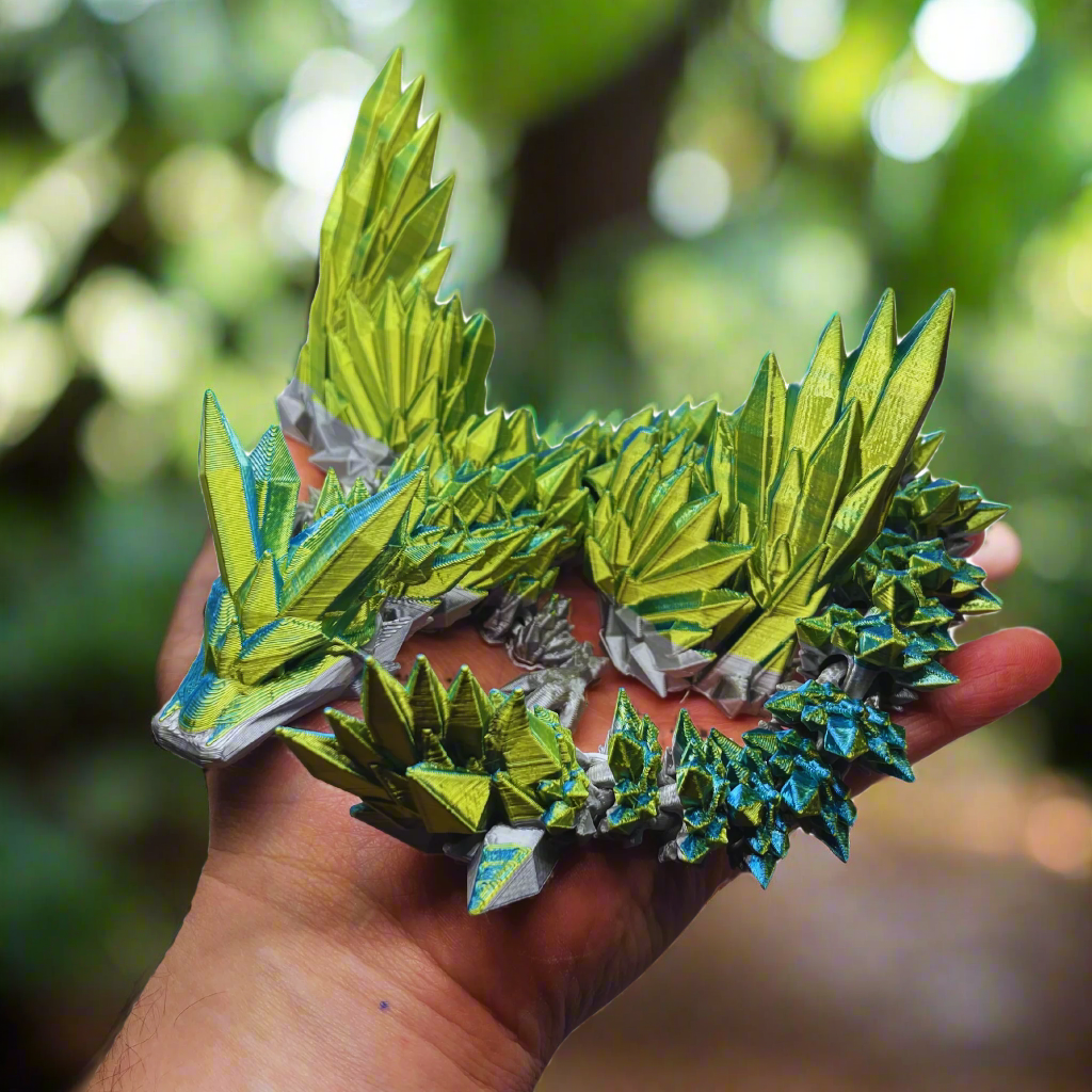 A detailed green and blue dragon figurine held in hand, showing its vibrant wings and intricate scale design.