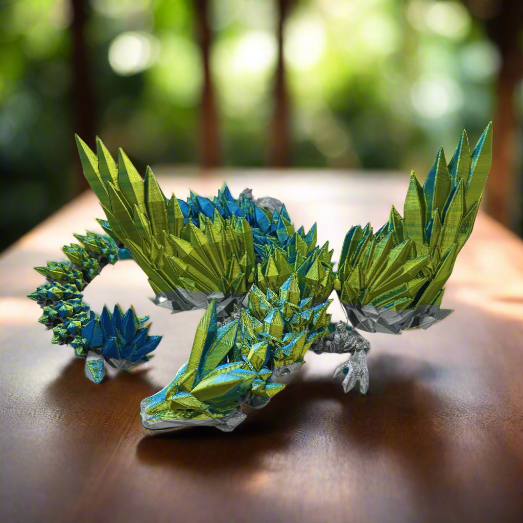 A side view of the green and blue 3D-printed dragon figurine, highlighting its sleek body and pointed tail.